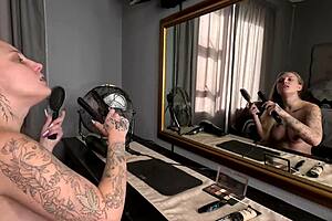 sexy tattooed blonde girl does hair and makeup naked